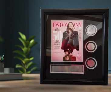 Custom frame displaying a FastCompany magazine cover and three commemorative medallions; black wood frame with silver accent matting.